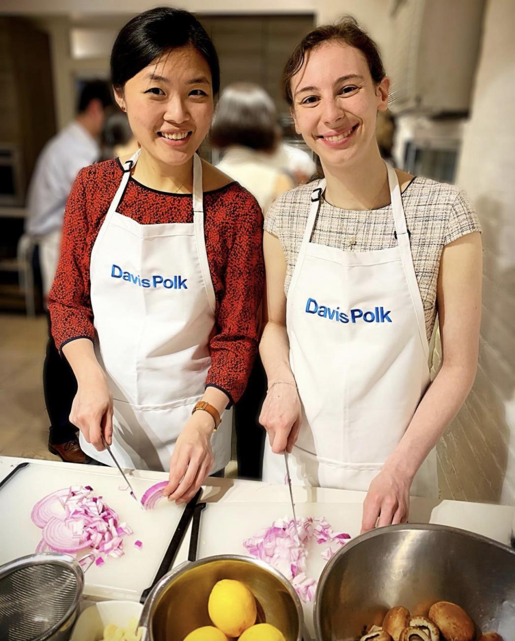Two Davis Polk summer associates wearing aprons at a cooking class