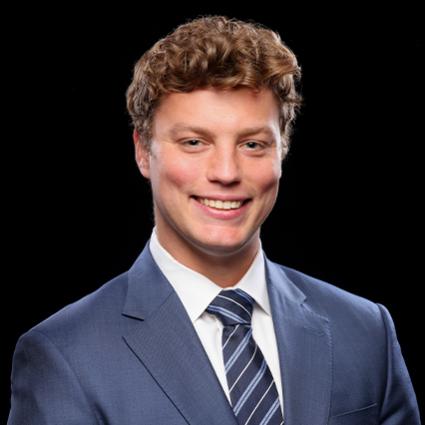 A smiling young man in a blue-gray suit